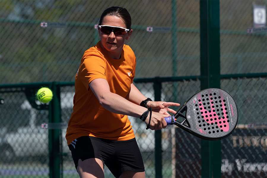 Woman hitting a shot in a competitive padel tournament match.