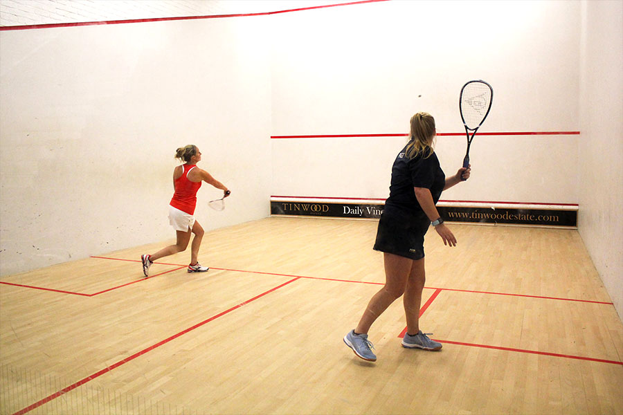 Female club squash players in a competitive match.