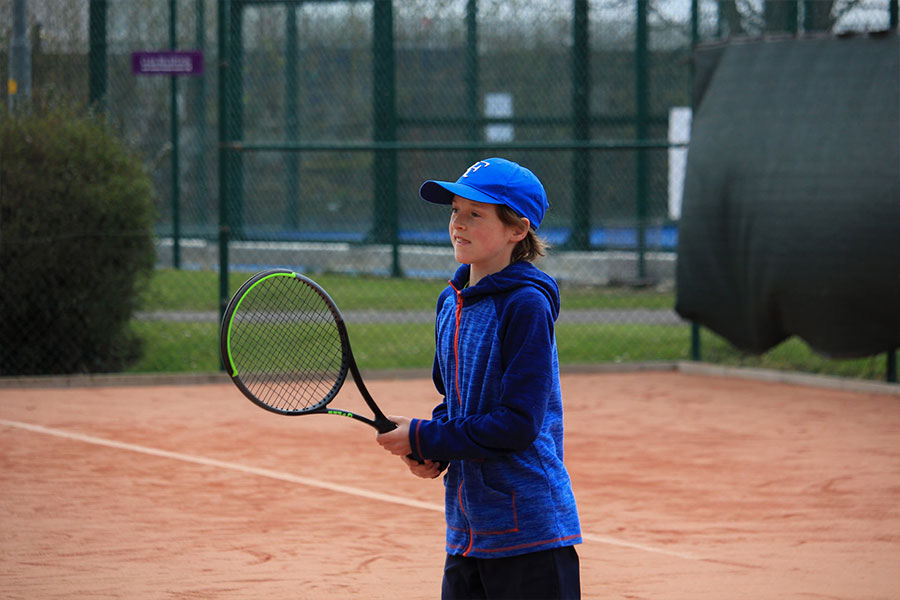 Junior tennis coaching session on artificial clay courts.